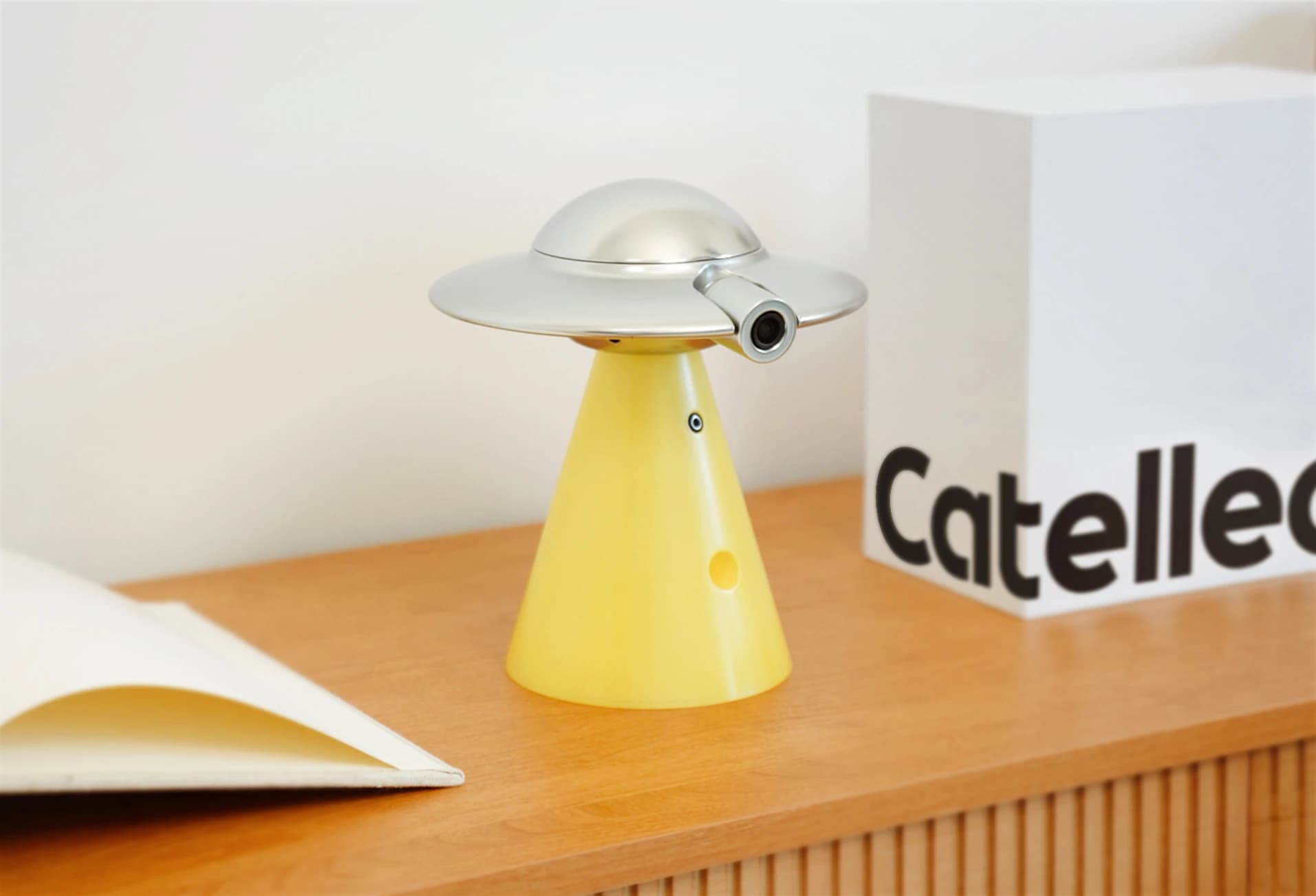 The Catellect UFO Home Hub and Collar on a wooden table in a warm home